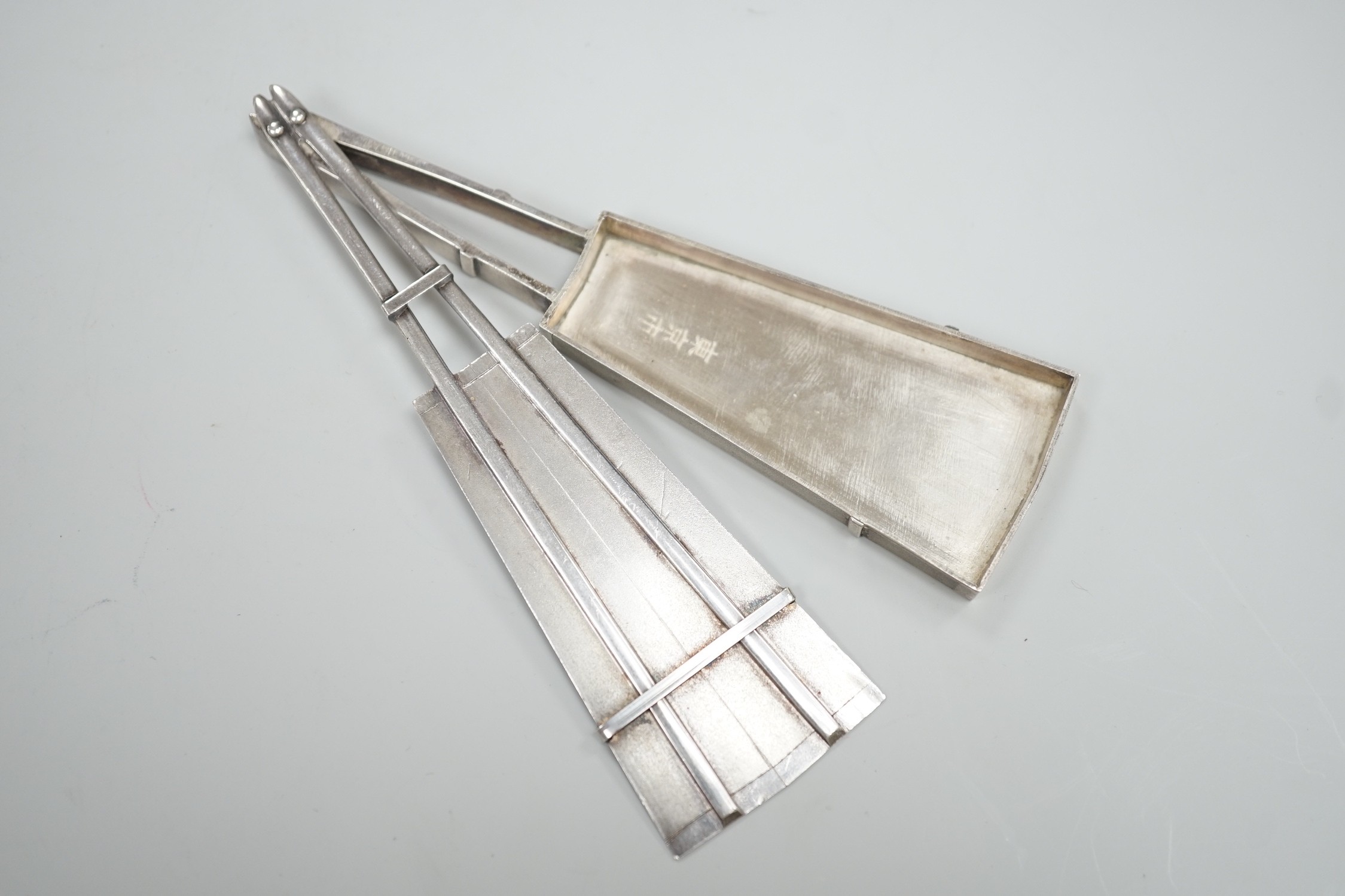 A 20th century Japanese white metal pill box, modelled as a fan with sliding panel, signed, 11.4cm.